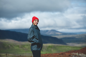 Fototapeta na wymiar Girl in warm clothing observing surroundings on background of mountains of Iceland.