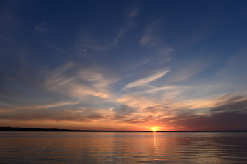 Fototapeta na wymiar Sunset in the clear blue summer sky above the lake