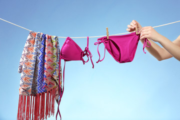 Female hands hanging out beachwear on a line. Summer vacation concept - obrazy, fototapety, plakaty