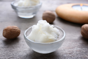 Shea butter in bowl and nuts on table