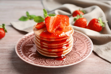 Plate with delicious pancakes on table