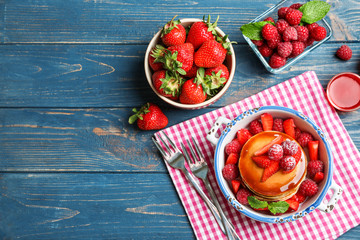Casserole with delicious pancakes on wooden background