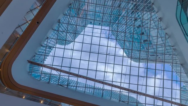 Time lapse of Looking up through the sun roof at office building at clouds and sunshine.