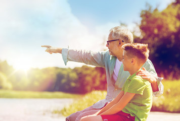 grandfather and grandson sitting on river berth