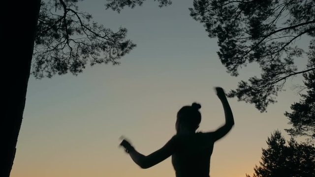 Young happy woman jumping, dancing and having fun in forest. Silhouette of woman. Freedom and happiness concept.