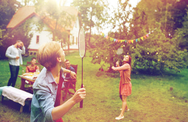 happy friends playing badminton at summer garden