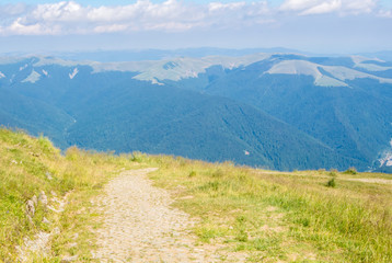 A tracking path over the mountain at Carpatians and beautiful blue sky at the background, Bucegi natural park near Sinaia, Romania, on sunny summer day.