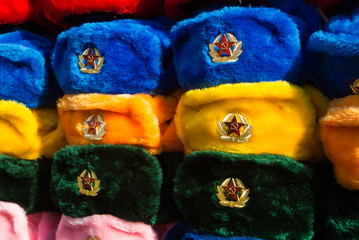 Rows of russian winter hats of different colors with army emblems at the street market at Old Arbat...