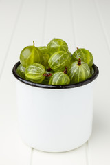 Fresh green gooseberries in an enamel mug