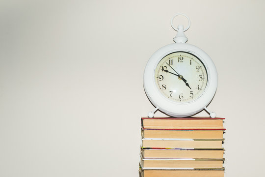 Still life round clock on stack of books. Education and learning concept. Invest time in studies. Time to upgrade ideas. Increase knowledge. Back to school. Copy space for text. Time read more