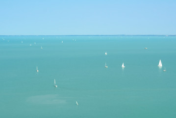 A view to turquoise transparent water of Balaton Lake with plenty of white yachts from above on summertime, Tihany, Hungary.