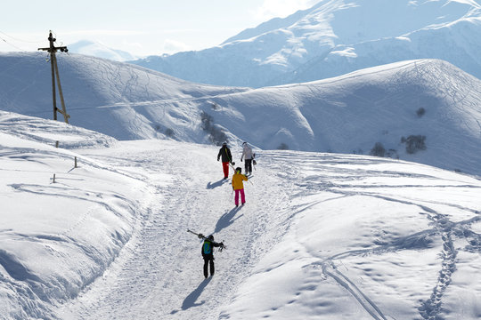 Skiers and snowboarders on snow road at sun winter morning