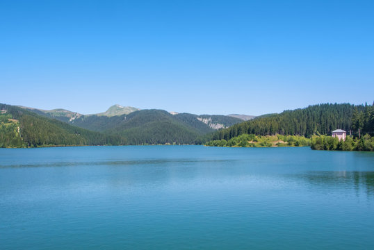 A view to Bolboci lake from the damb with carpathian mountains at the background, Sinaia, Romania.
