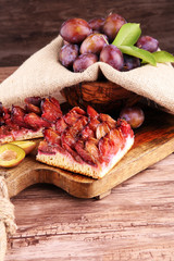 rustic plum cake on wooden background with plums around