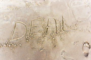 Deal written in the sand on a sunset beach