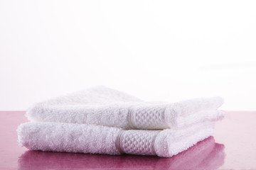 Spa. Two white towels on a pink marble table. White background.