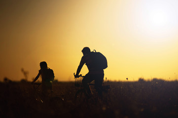 Dad and daughter travel by bicycle at sunset