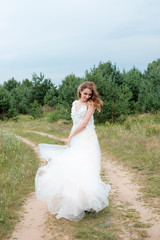 Fototapeta na wymiar young pretty woman (bride) in white wedding dress outdoors, make up and hairstyle