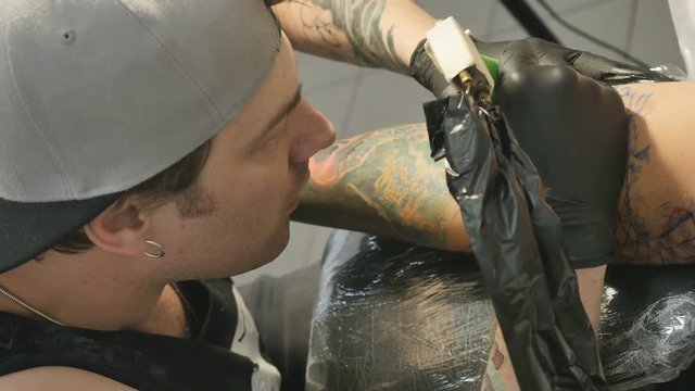 Tattoo artsit is making the tattoo on the arm