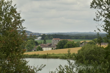 Fototapeta na wymiar Le village de Champagne avec son église romane derrière le plan d'eau ,au Périgord Vert 
