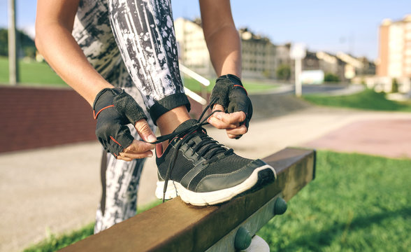 Low section of woman tying shoelaces while exercising at park