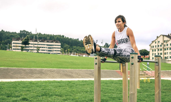 Young woman exercising on parallel bars at park