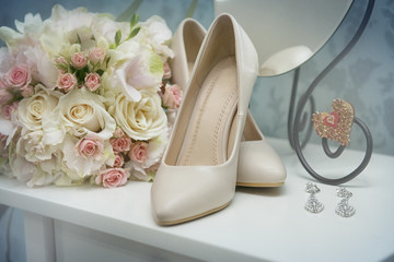 Wedding shoes with bouquet and earrings in the interiors