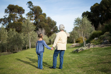 Obraz premium Granddaughter and grandmother standing together in garden