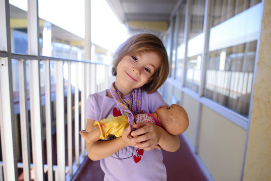 Portrait of happy girl carrying doll in corridor