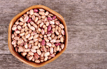 Colored beans in a wooden bowl on an old wooden background