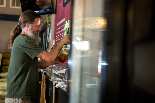 Side view of man pouring beer from tap