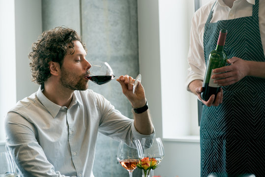 Bartender standing by customer drinking wine in tasting room