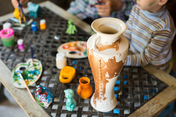 Father and son paint a vase