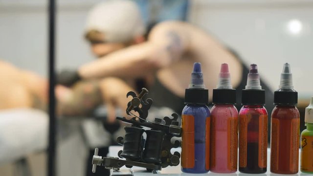 Bottles with colorful paints and tattoo machine