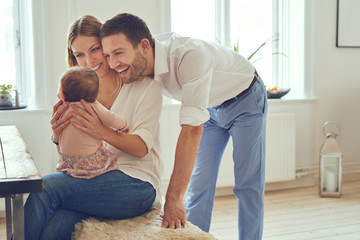 Smiling young parents holding their adorable baby girl