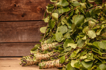 new brooms for a bath birch and oak branches on dark brown wooden background