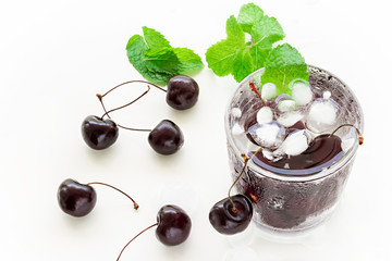 Cold refreshing detox water with cherry, mint and ice cube in glass. Top view.  Concept healthy food, diet and fitness. White background.