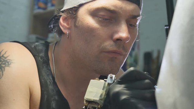 The tattoist makes tattoo on the man's hand