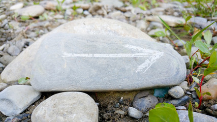 Painted arrow on stone show direction on dry rocks close to river side close up