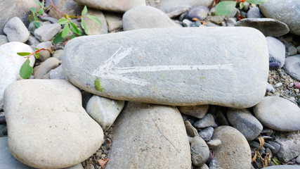 Painted arrow on stone show direction on dry rocks close to river side on stone pile