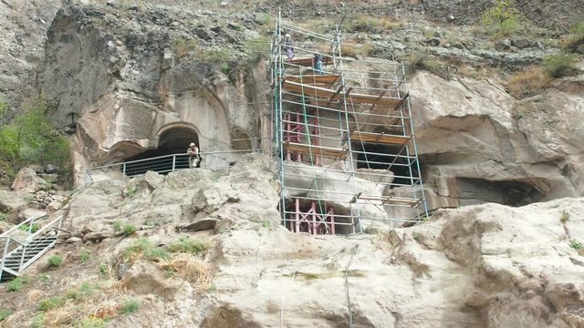 Workers make repairs on scaffolding Vardzia cave monastery