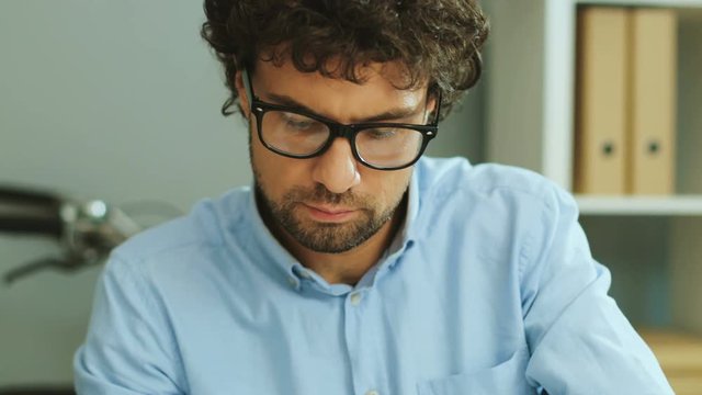 Portrait of young man in the glasses working on the new project on the office background.