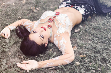 Belly dancer lying in grass and relaxing