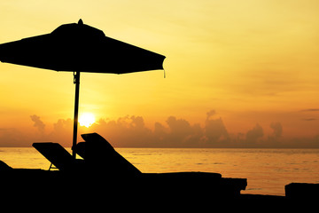 Fototapeta na wymiar Silhouette, beach chairs and umbrellas at the seaside at sunrise
