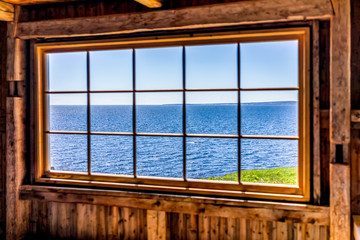 Looking through old window of house with cliff and ocean view in Bonaventure Island, Quebec, Canada