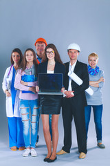 Smiling businesswoman with laptop and group of industrial workers