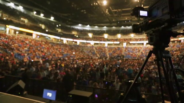 Shot of Video Camera taking video of packed coliseum before a concert