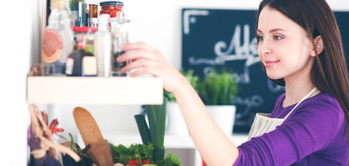A young woman choosing spices in her kitchen .