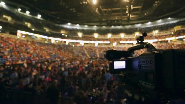 Shot of Video Camera taking video of crowd at packed venue before show starts