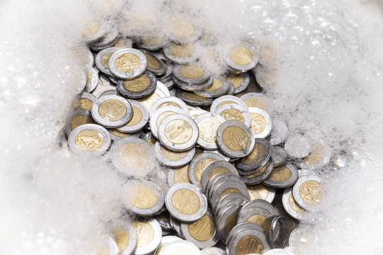 conceptual image of money laundering, mexican pesos coins with soap foam